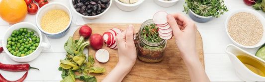 Bouteille de kombucha Galatea, bocaux de pickles et bol de vinaigrette sur une table de cuisine