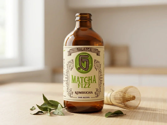 Bouteille Stubby ambrée Matcha Fizz de Galatea Kombucha, étiquette crème avec nom en vert matcha, feuilles de thé et fouet à matcha en bambou