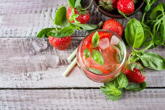 Verre de kombucha fraise basilic Galatea sur table d'été avec fraises et basilic frais